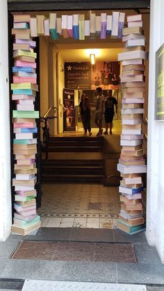 two people are standing in the doorway of a library with many books stacked on top of each other