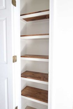 an empty pantry with wooden shelves and white walls