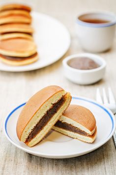 a plate that has some kind of sandwich on it next to two cups of coffee