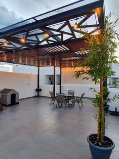 an outdoor covered patio with chairs and table next to potted plant on the floor