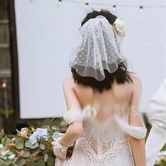 the back of a bride's dress as she walks down the aisle with her veil over her head