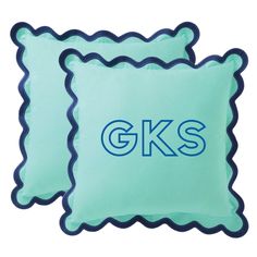 two blue pillows with the letters gks on them and scalloped edges are shown