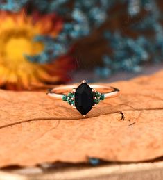 a black diamond ring sitting on top of a leaf