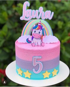 a pink and blue cake with a unicorn on it's top that says laura 5