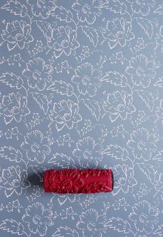 a red piece of paper sitting on top of a blue wallpaper covered in white flowers