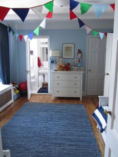 a room with blue walls and wooden floors, decorated with bunting flags on the ceiling