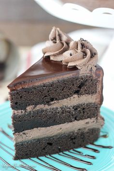 a piece of chocolate cake with frosting on a blue plate next to a fork