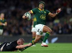 a rugby player is running with the ball as he tries to get past another player