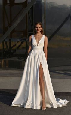 a woman wearing a white dress with a slit in the side and one leg up