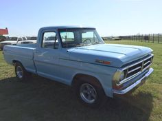 an old pick up truck parked in a field with other trucks behind it on a sunny day