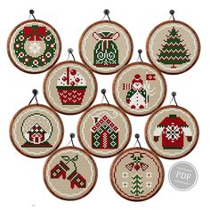 six cross stitch christmas ornaments hanging from hooks