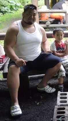 a man sitting on top of a bench next to a little boy