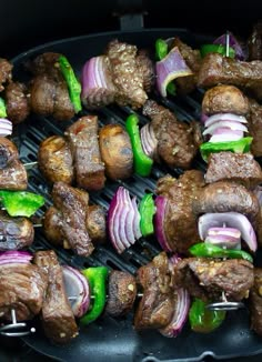 several skewers of meat and vegetables cooking on a grill