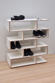 several pairs of shoes are sitting on top of a shelf in front of a white wall