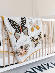 a white crib with a butterfly quilt on it