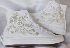 a pair of white high top sneakers with flowers on the side and sequins