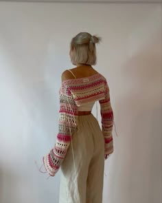 a woman standing in front of a white wall with her back turned to the camera