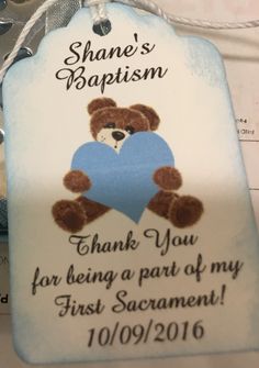 a blue and white tag with a teddy bear holding a heart