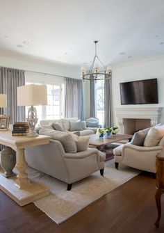 a living room filled with furniture and a flat screen tv mounted on the wall above a fireplace