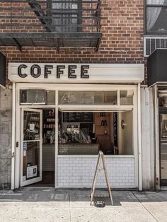 an empty coffee shop on the corner of a street in front of a brick building