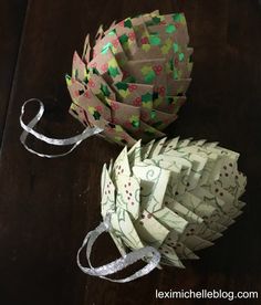 two origami flowers on a table next to each other with ribbons around them