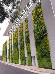 a building covered in green plants on the side of it's face and sides