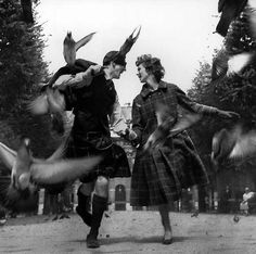 two people dressed in old fashioned clothing with birds flying around them and one man is holding the woman's hand