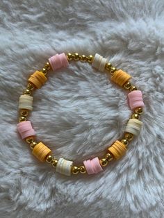 a bracelet with gold and pink beads on a white furnishce background, close up