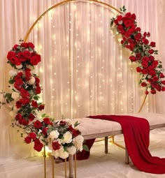 a white bench with red and white flowers on it next to a gold circular arch