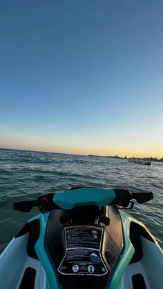 the back end of a jet ski in the water at sunset or sunrise, looking out to sea