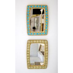 two square mirrors with blue and gold trim on the wall next to a white couch