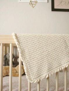 a crocheted blanket draped over the top of a baby's crib