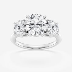 three stone engagement ring with diamonds on the sides and an oval diamond in the center