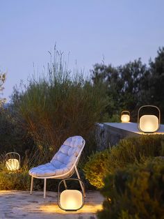 some lights that are on the ground near a chair and tree in the evening time