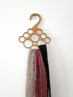 a wooden hanger with two scarves hanging from it's side on a white wall