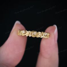 a hand holding a gold ring with diamonds