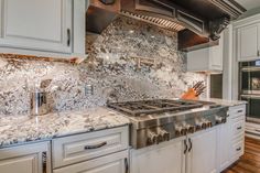 a stove top oven sitting inside of a kitchen next to white cabinets and wooden floors