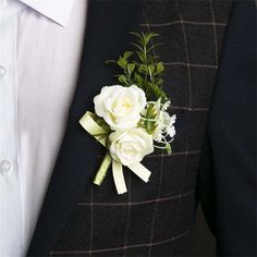 a boutonniere with white flowers and greenery on it's lapel