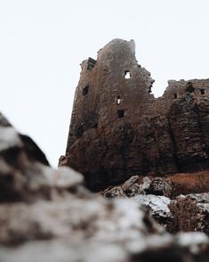 an old stone castle sitting on top of a rocky hill next to snow covered ground