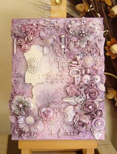 an art work with flowers and buttons on a easel next to a flower arrangement