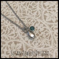 a silver necklace with a green stone on the bottom and a chain attached to it