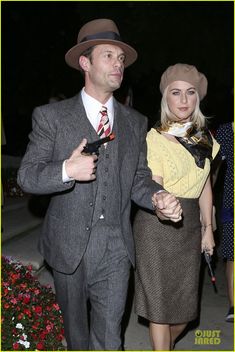 a man in a suit and tie walking next to a woman