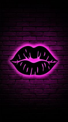 the neon lips are glowing against a brick wall