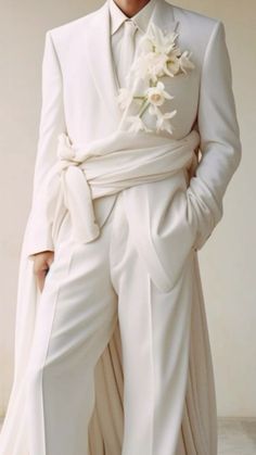 a man in a white suit and tie with flowers on his lapel