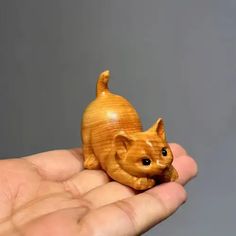 a hand holding a small wooden cat figurine