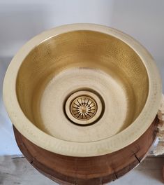 a gold colored sink sitting on top of a wooden stand