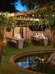 an outdoor dining area is lit up with candles and greenery as well as the pond