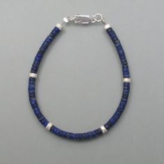 This lapis lazuli bracelet has a classic design throughout. Small rolls of lapis lazuli line up and are interrupted at regular intervals by equally shaped silver parts. The intense and dull blue of the lapis lazuli and the cool silver unite here to a wonderfully uncomplicated and stylish bracelet. Here you will find the matching necklace or matching earrings. Dimensions: Diameter of the rollers: 3.8 mm, length: 19 cm Blue Natural Stones Sterling Silver Bracelets, Blue Lapis Lazuli Bracelets With Polished Beads, Silver Lapis Lazuli Bracelet, Hand-strung, Silver Lapis Lazuli Hand-strung Bracelets, Silver Hand-strung Lapis Lazuli Bracelet, Blue Beaded Bracelets With Sterling Silver Clasp, Blue Sterling Silver Bracelets With Polished Beads, Silver Beaded Bracelet With Lapis Lazuli And Natural Stones, Blue Sterling Silver Bracelets With Gemstone Beads