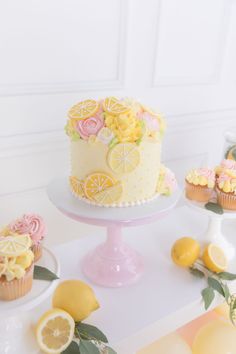 there is a cake and cupcakes on the table with lemons around it