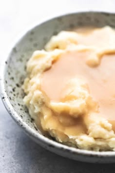 a bowl filled with mashed potatoes and gravy on top of a table